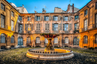 Abandoned fountain against historic building