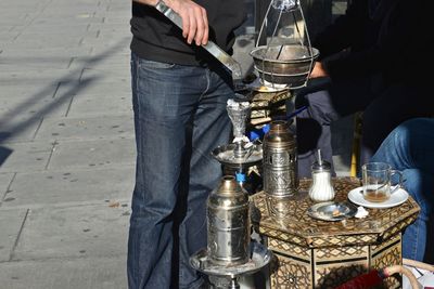 Midsection of man making drink while standing at sidewalk cafe