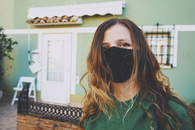 Portrait of young woman standing against wall