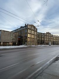 Road by buildings against sky in city