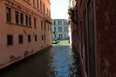 Canal amidst buildings in city against sky