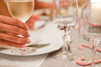 Midsection of woman holding drink in glass on table