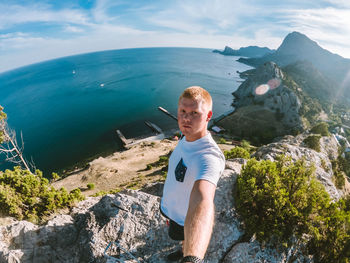 Young man looking at sea against mountain