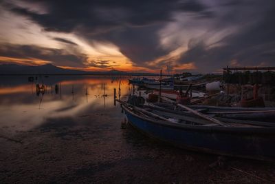 Boats moored on sea against sky during sunset