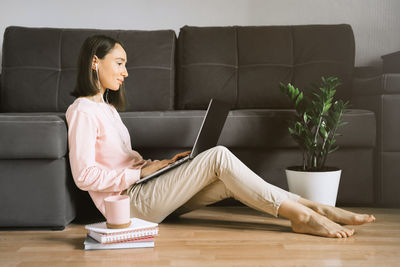 Full length of woman sitting on sofa at home