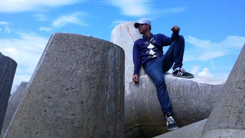 Full length of young man standing on retaining wall against sky