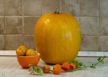 Close-up of orange fruits on table against wall