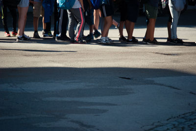 Low section of people standing in line on road
