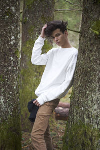 Young woman standing on tree trunk in forest