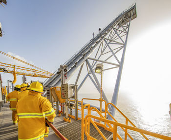 Rear view of man working at construction site against sky