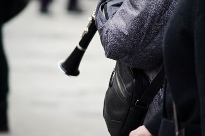 Close-up of person holding flute and standing on street