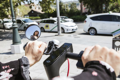 Young woman with e-scooter in the city, rear-view mirror