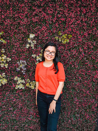 Portrait of smiling young woman standing against plants