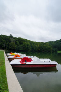 Boat moored by lake against sky