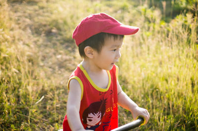 Cute smiling boy riding push scooter against plants