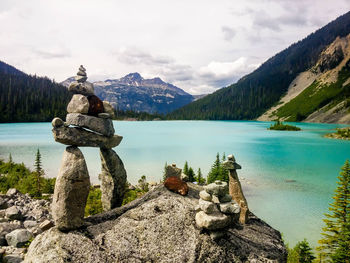 Stones stacked on rock by lake against sky