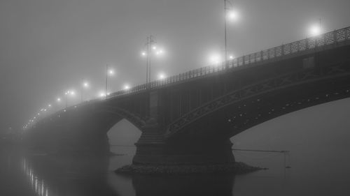 Bridge over river against sky at night