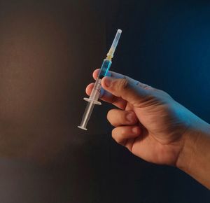 Close-up of person holding cigarette against black background