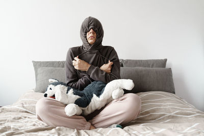 Rear view of woman sitting on bed at home