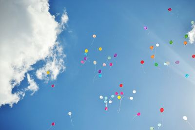 Low angle view of balloons flying against blue sky