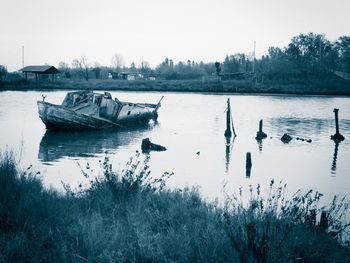 Boats moored in river against sky during winter