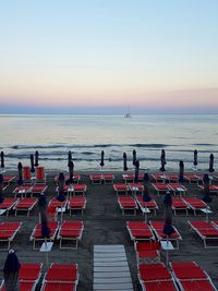 People at beach against clear sky during sunset