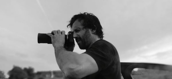 Side view of man photographing through camera