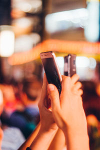 Cropped hand of man using mobile phone at night