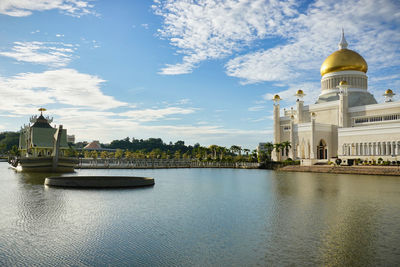 Buildings by river against sky