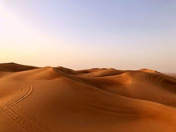 Scenic view of desert against clear sky during sunset