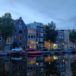 Buildings by canal against sky in amsterdam city