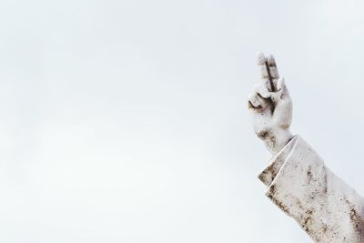 Arm of a statue against white background