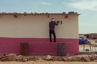 Rear view of man photographing against wall