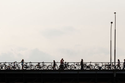 Man and woman walking on bridge against sky