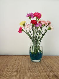 Flowers in vase on place mat against wall