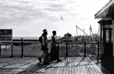 Rear view of people standing by sea against sky