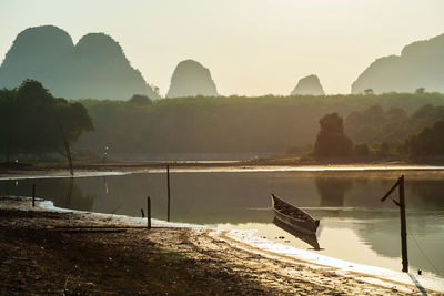 Wooden boat on nong thale lake with limestone mountains at sunrise, krabi, thailand. 