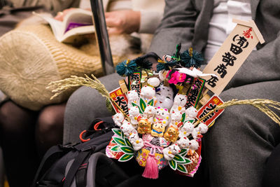 Man with maneki neko by woman sitting in train