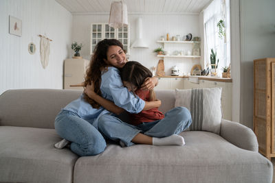 Young woman using phone while sitting on sofa at home