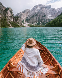 Rear view of woman wearing hat sitting in boat on lake