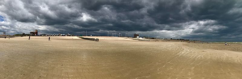 Panoramic view of beach against storm clouds