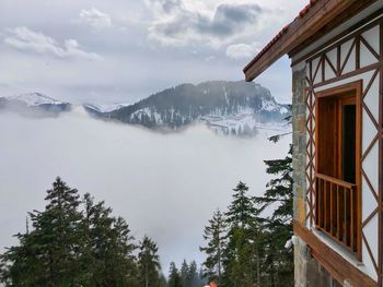 Scenic view of snow covered mountains and trees against sky