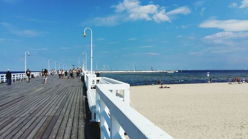 People on wooden pier over sea against sky