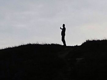 Silhouette of man standing on landscape against sky