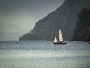 Sailboat sailing on sea against sky at sunset