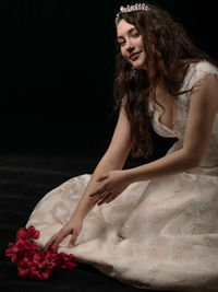 Beautiful young woman sitting against black background