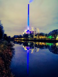 Illuminated tower by lake against sky at night