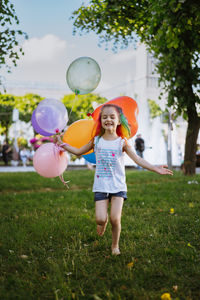 Cute little caucasian girl with colourful dyed hair walking barefoot with baloons