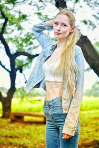 Beautiful young woman standing against tree