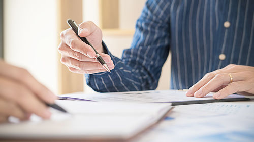 Midsection of man holding umbrella on table